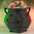 Black skull-shaped candy bowl filled with colorful candies on a gradient background