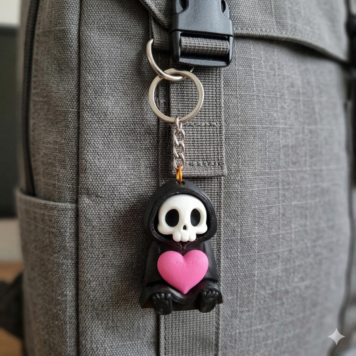A Love Reaper keyring clipped to a grey backpack strap
