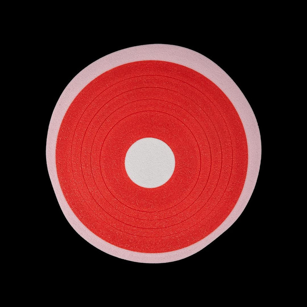 A pork chop coaster from above: red with a white centre