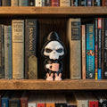 Coffin Break grim reaper figure with a pink mug and bunny slippers on a bookshelf