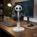 White skull headphone stand holding black headphones on a gaming desk