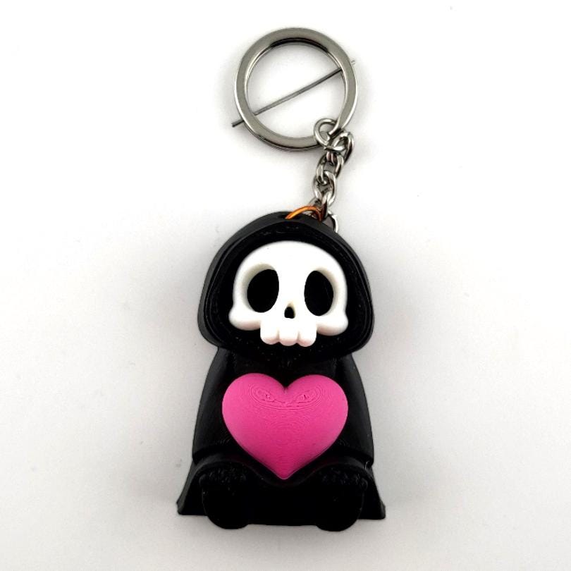Sitting with Heart keyring: a sitting grim reaper hugging a pink heart