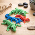 Articulated geckos in green, blue and red on a wooden table
