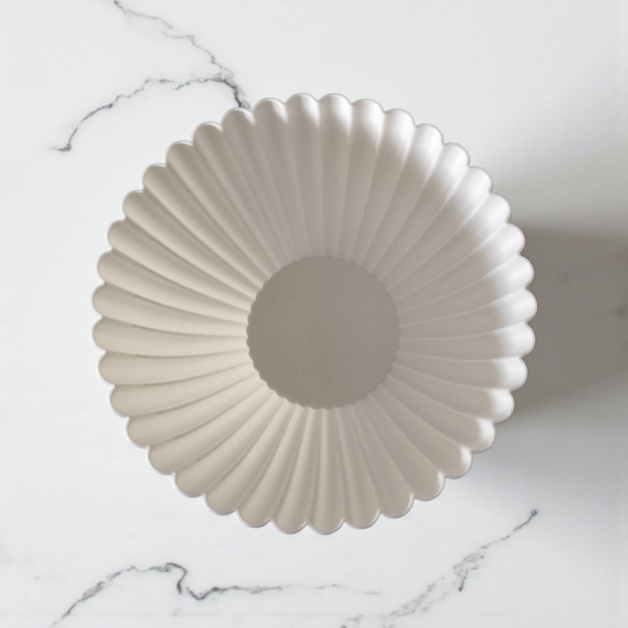 White plastic bowl with a textured design on a marble surface