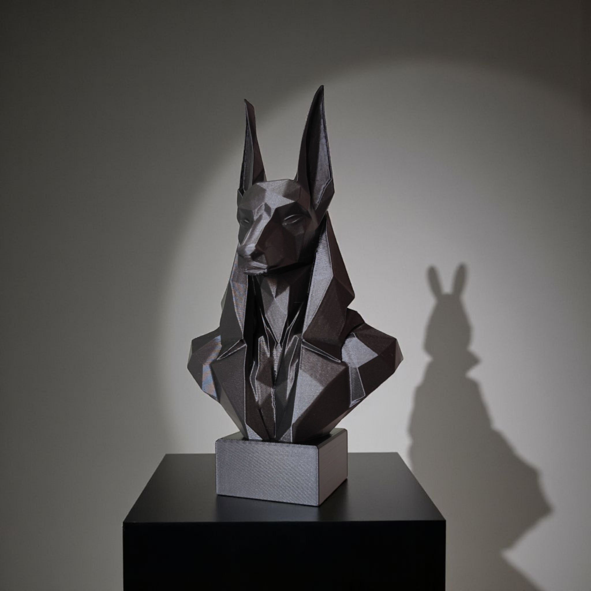 Geometric sculpture of a dog head on a black pedestal with a gray background