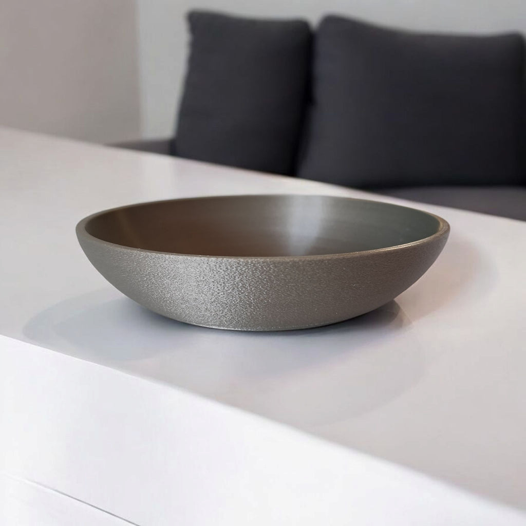 Gray ceramic bowl on a white surface with a blurred background