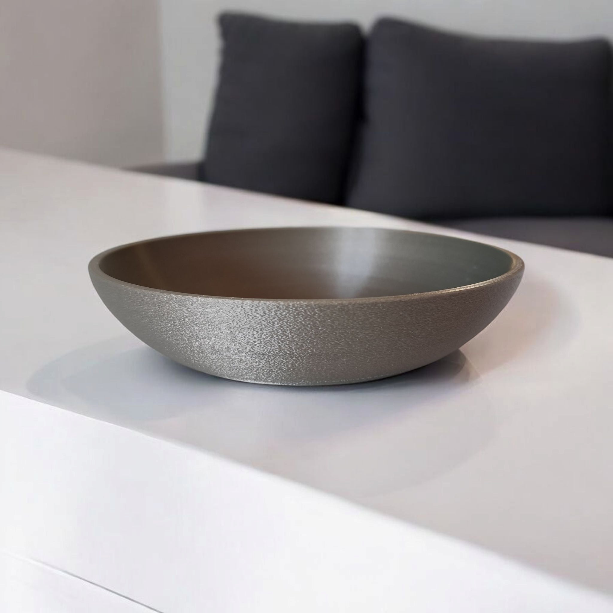 Gray ceramic bowl on a white surface with a blurred background