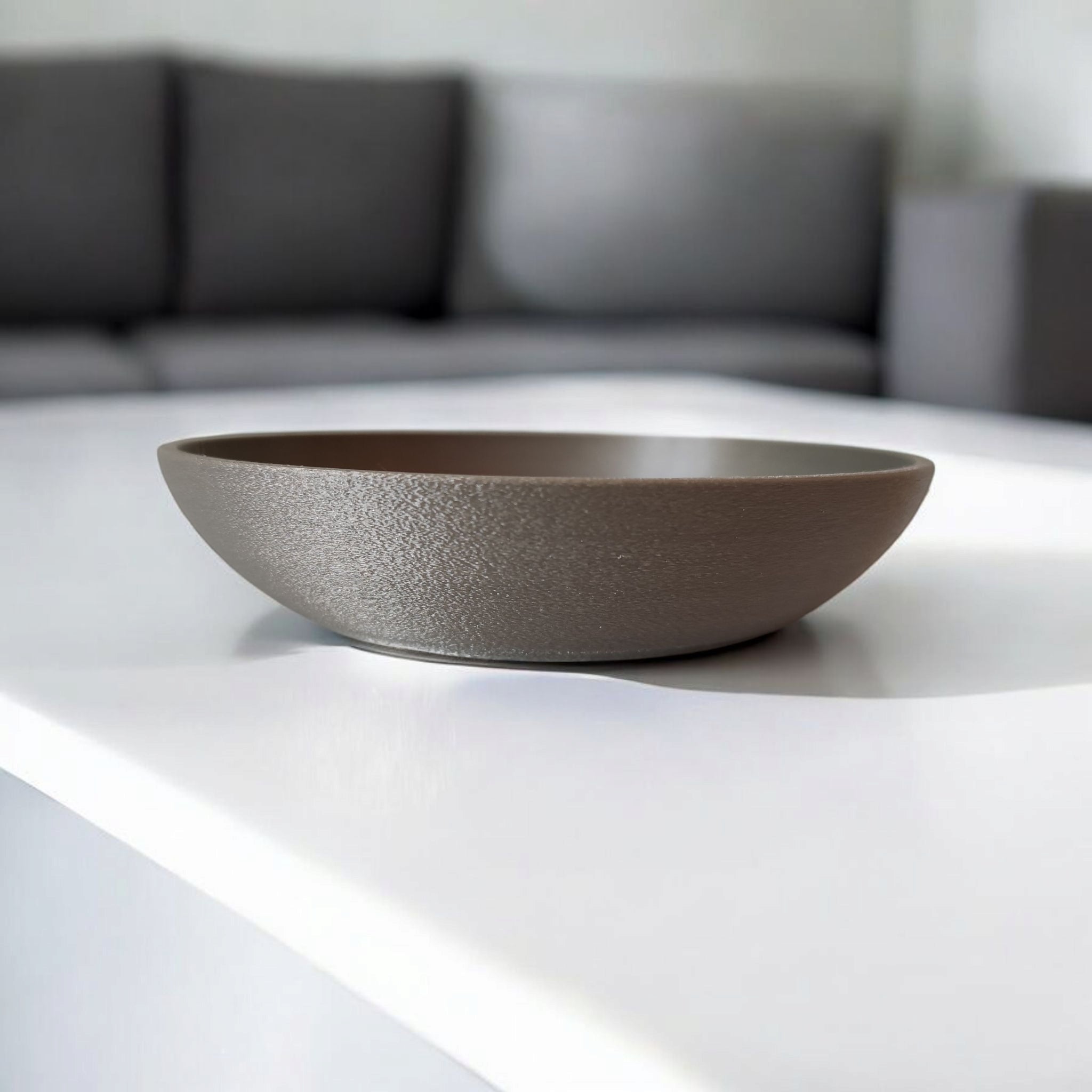 Brown bowl on a white surface with a blurred gray sofa in the background