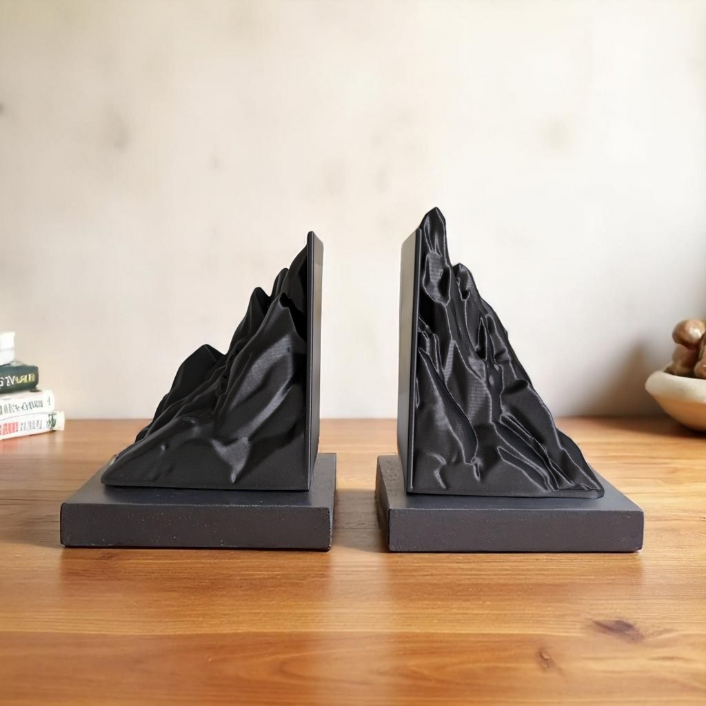 Black mountain-shaped bookends on a wooden surface with a neutral background