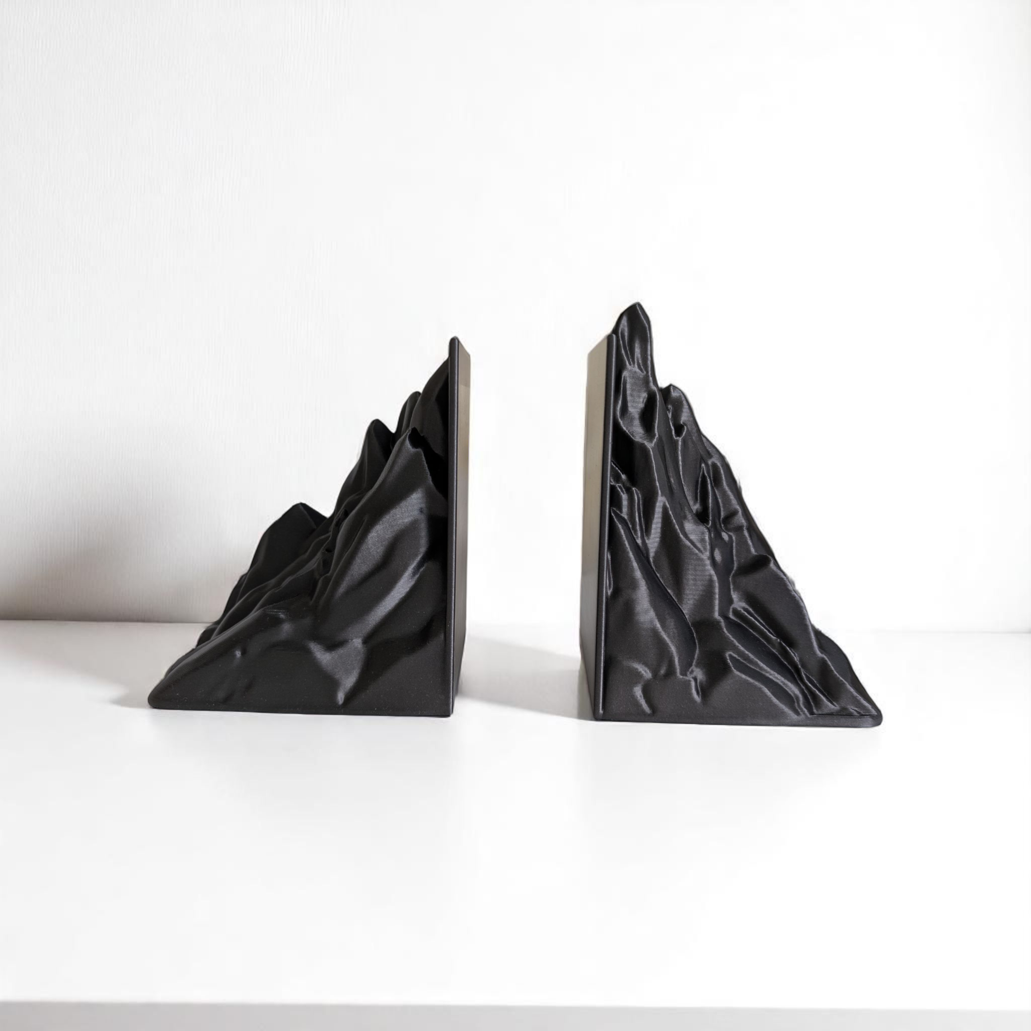 Black mountain-shaped bookends on a white surface with a white background