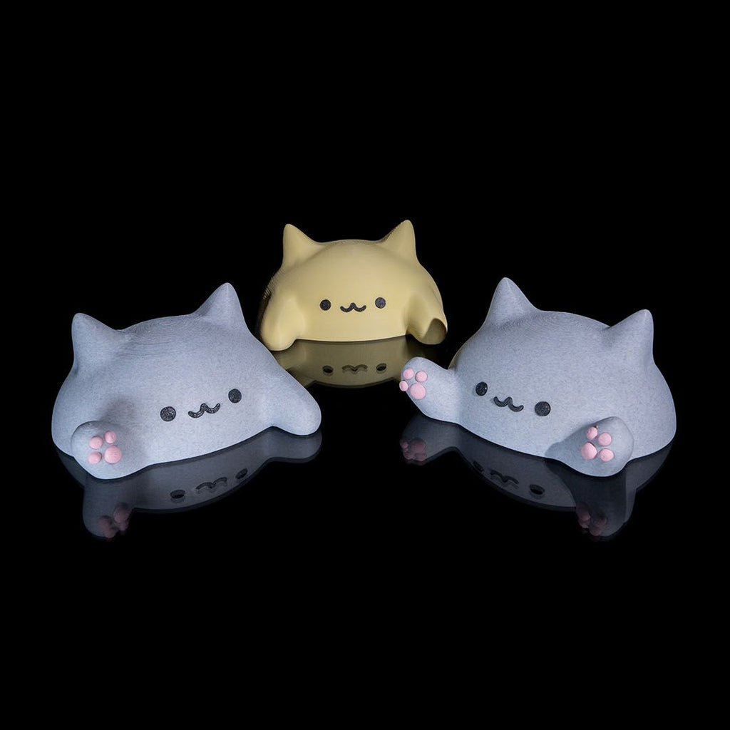 Three cute, cartoon-like cat figurines with simple facial expressions on a black background.