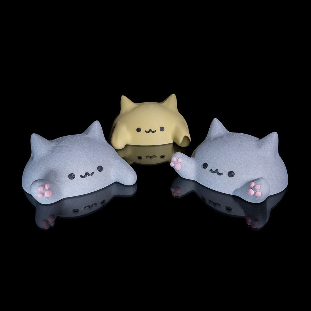 Three cute, cartoon-like cat figurines with simple facial expressions on a black background.