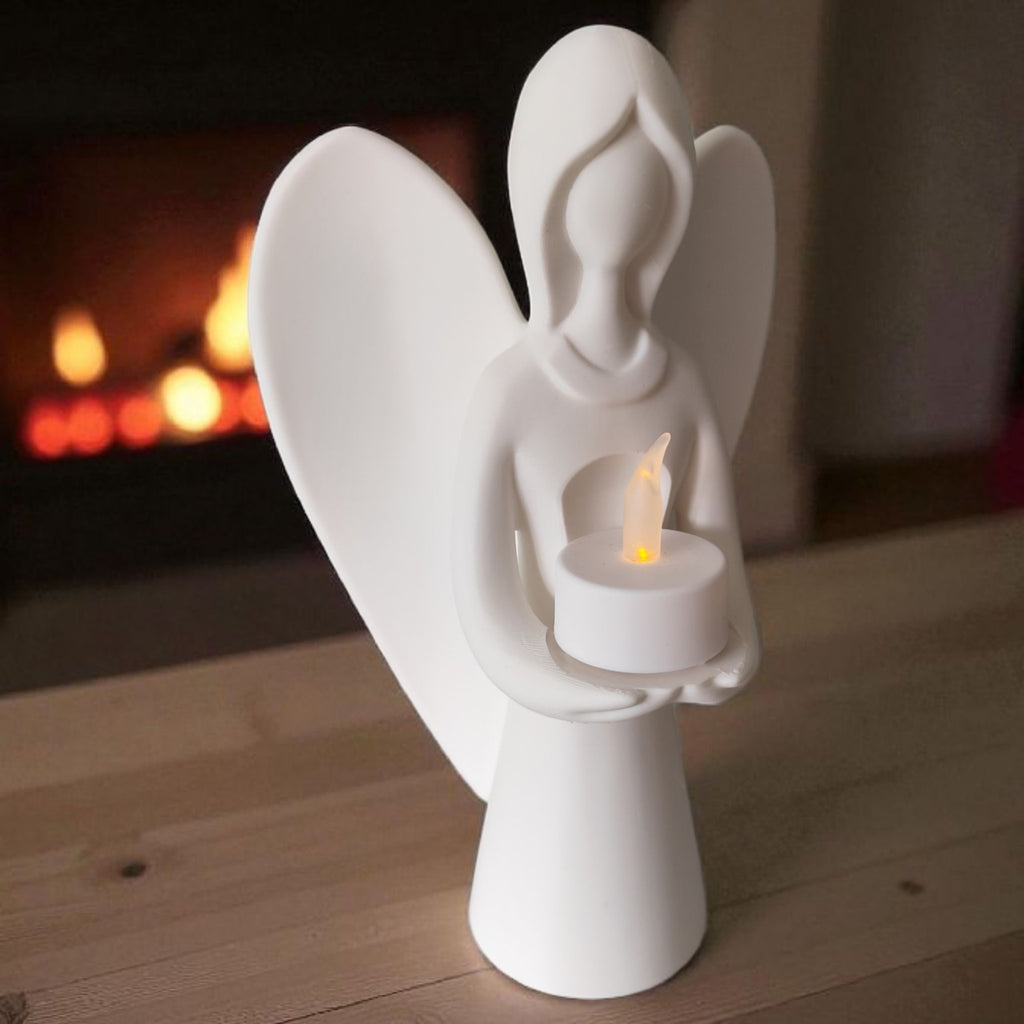 White angel figurine holding a candle on a wooden surface with a fireplace in the background