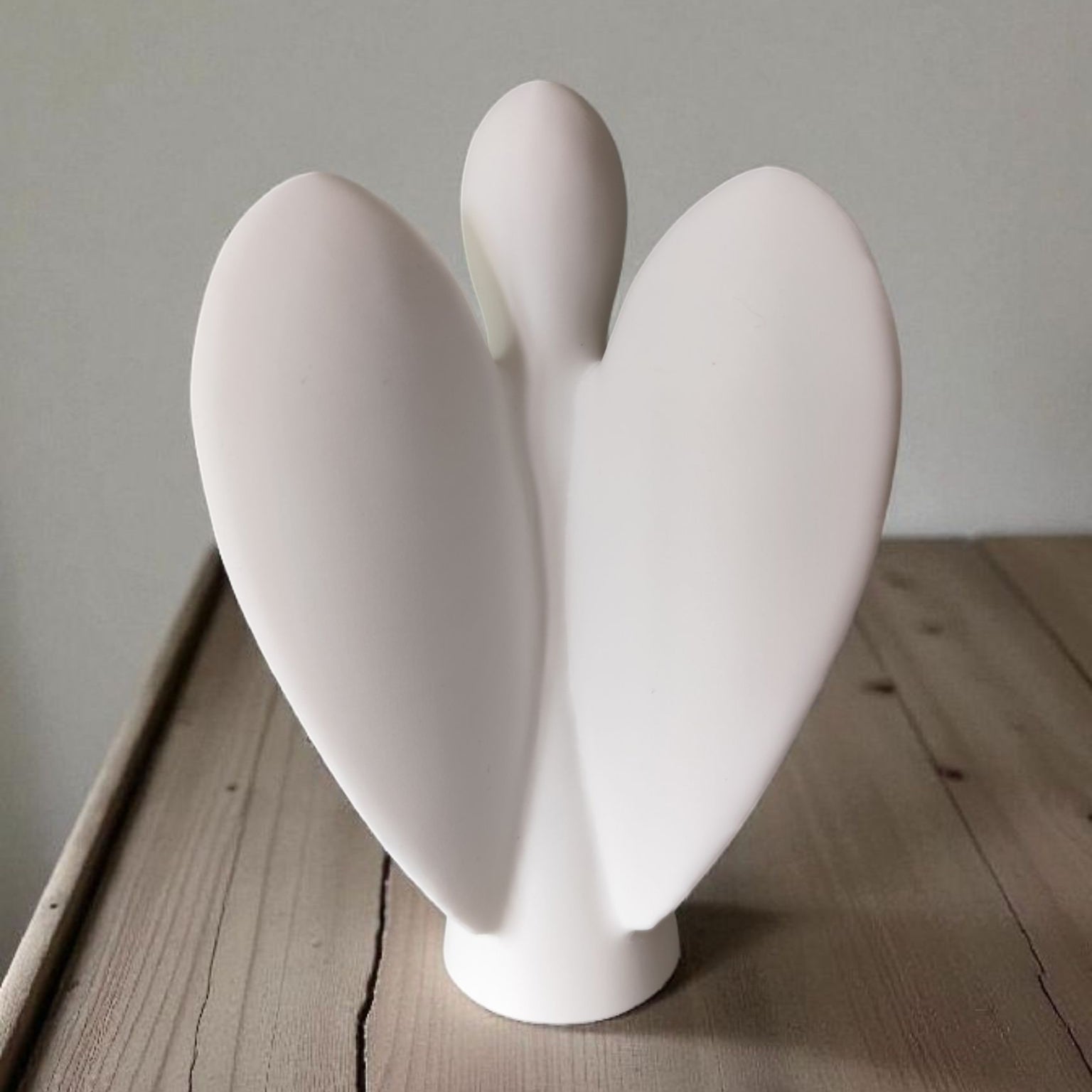 White ceramic vase with a unique design on a wooden surface.