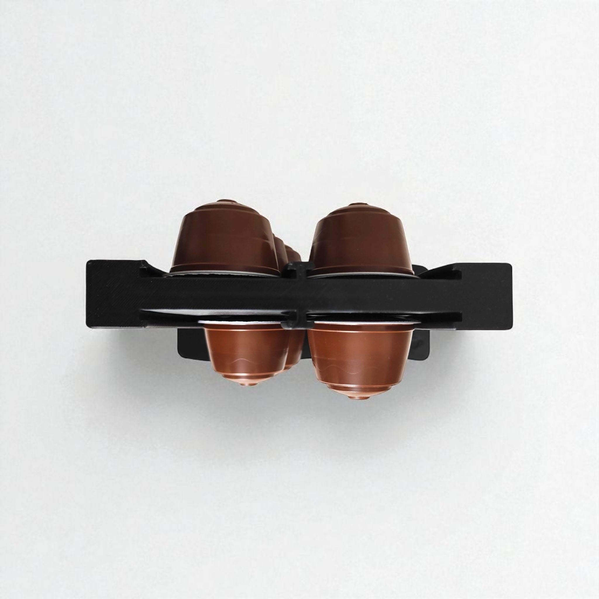 Black holder with four brown coffee pods on a white background
