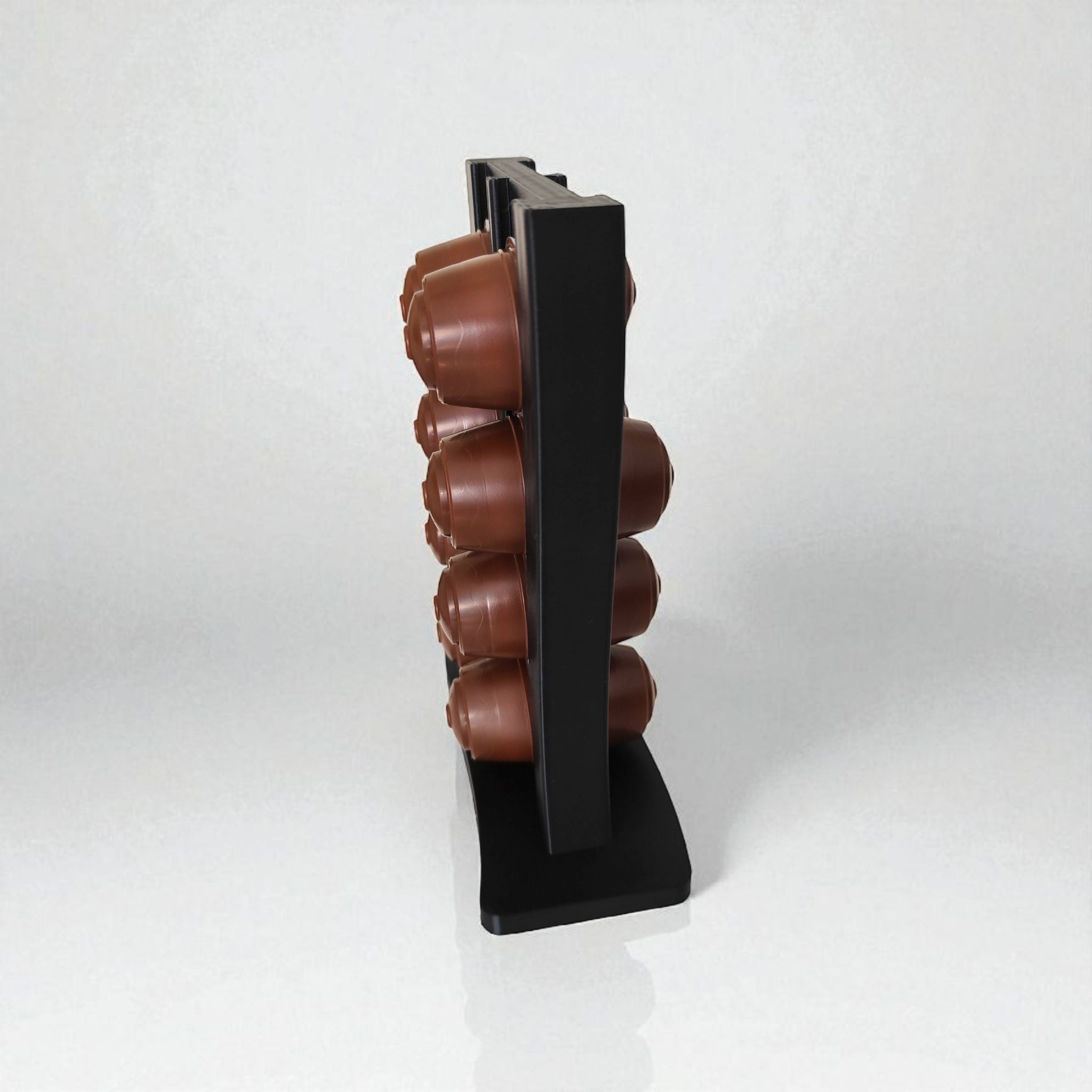 Stack of brown coffee capsules on a black stand against a white background