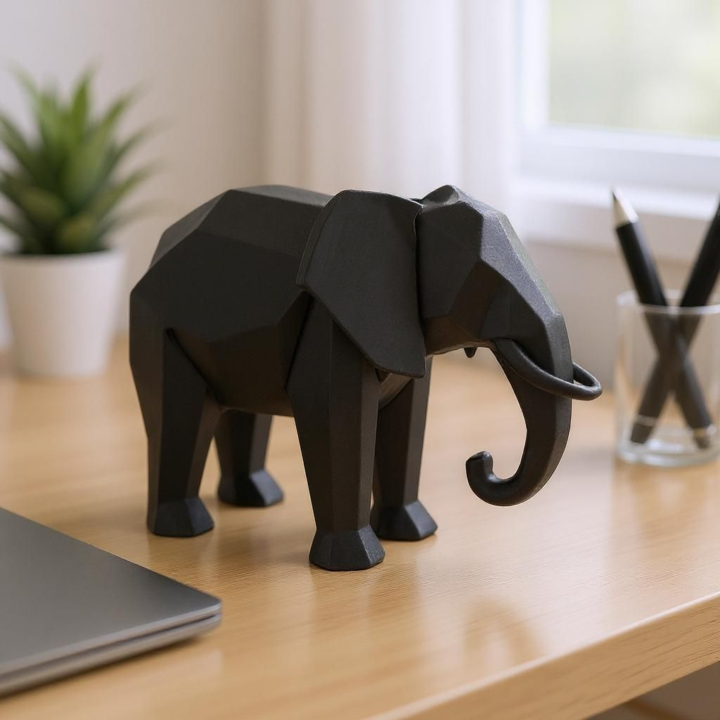 Black elephant figurine on a wooden desk with a plant and glasses in the background