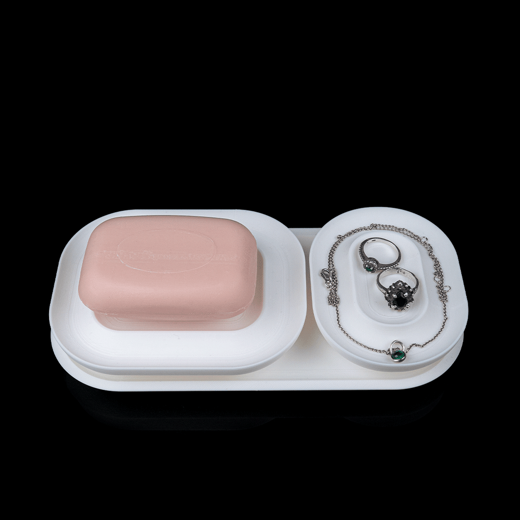 White jewelry tray with a pink soap bar and jewelry on a black background