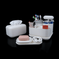 White bathroom organizer with various items including a tissue box, soap, and toothbrush holder on a black background.