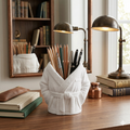 Desk with a white robe-style holder containing pens and pencils, books, and a lamp.