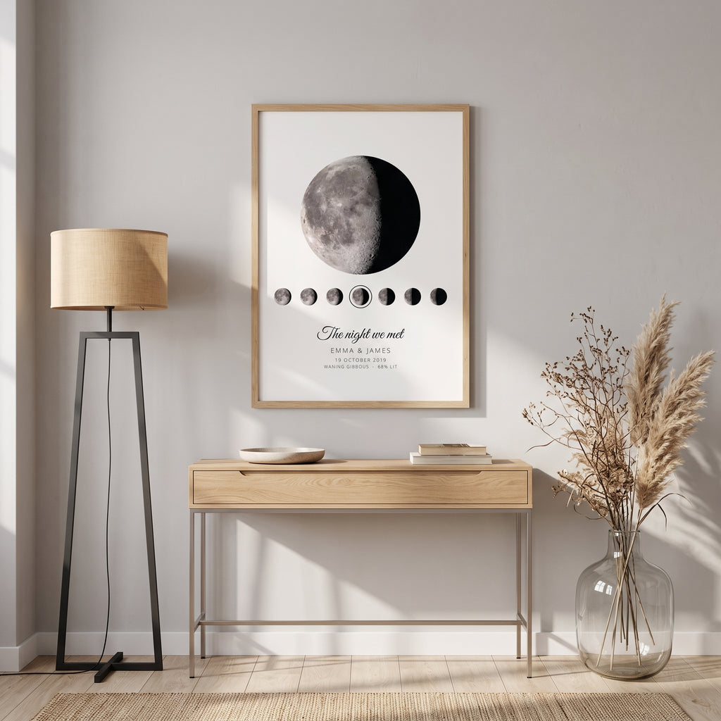 White personalised moon phase print in an oak frame above a console table: the real Moon and the nights either side, The night we met, Emma & James