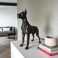 Black dog statue on a table with books and a plant pot in a living room setting