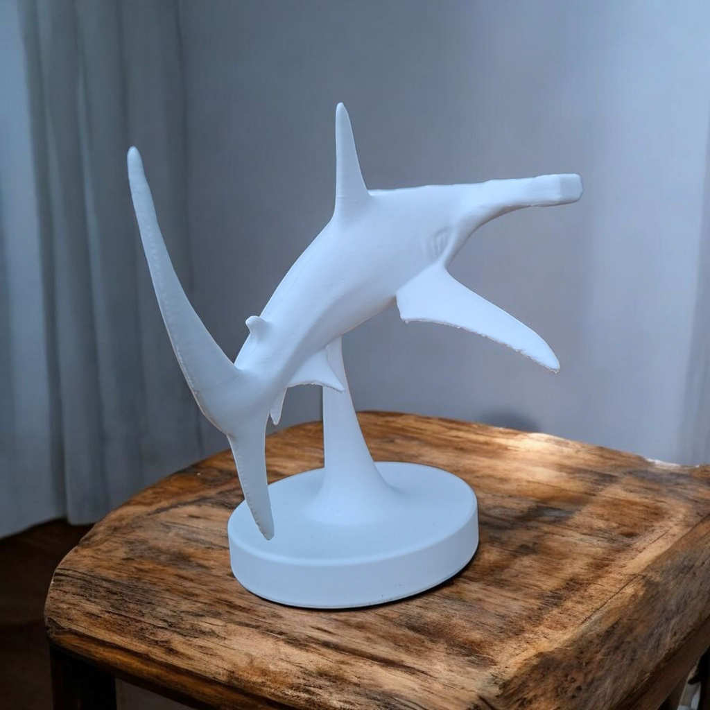White shark sculpture on a wooden table with a gray curtain background