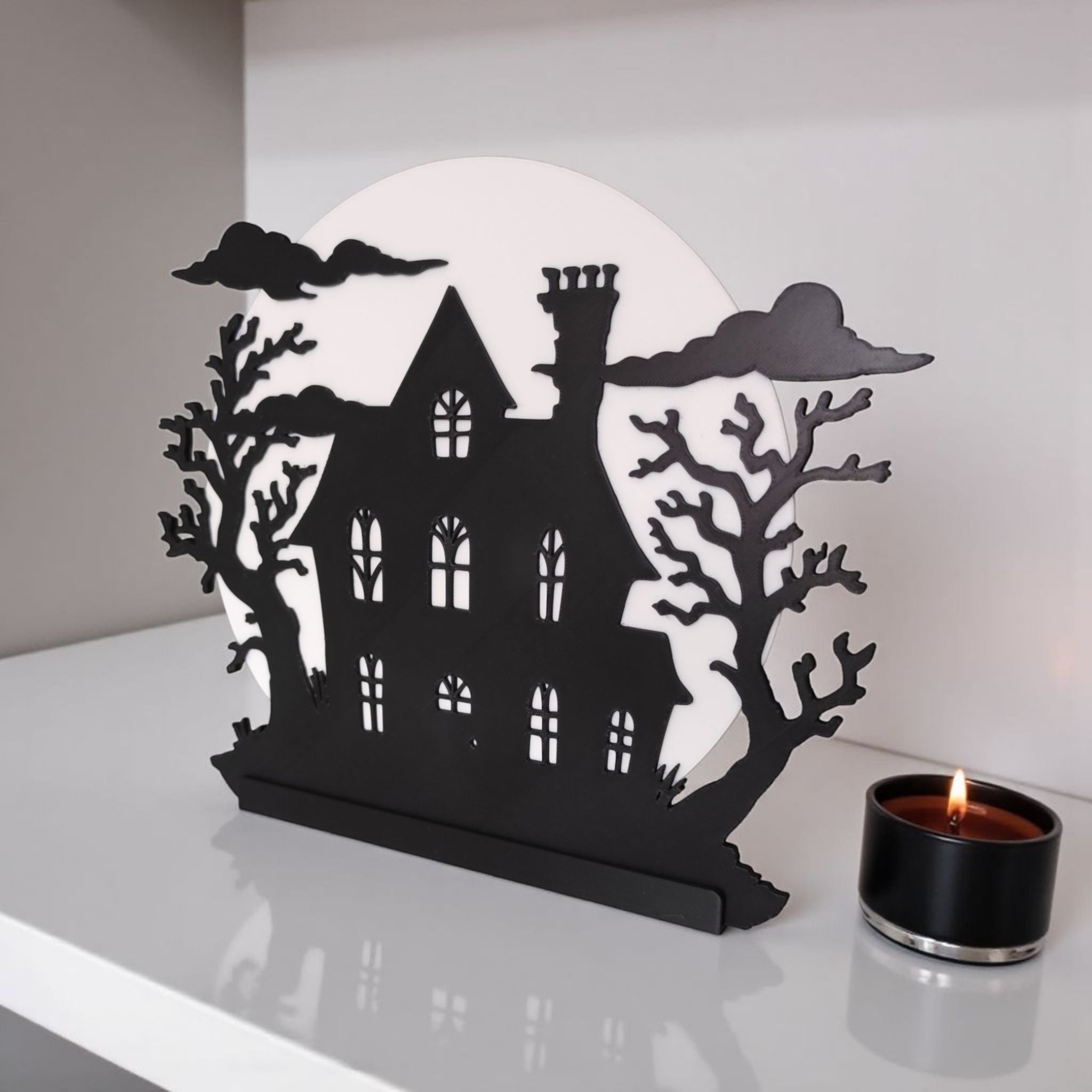 Decorative Halloween house silhouette with a candle on a white surface