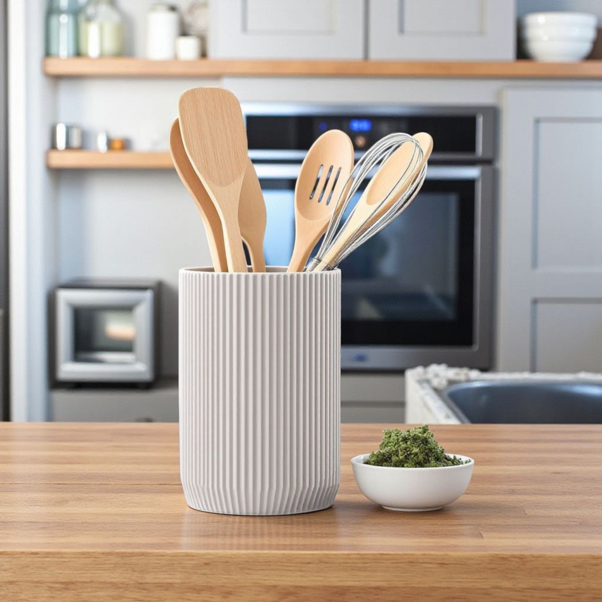 White utensil holder with wooden spoons and a fork on a kitchen counter.