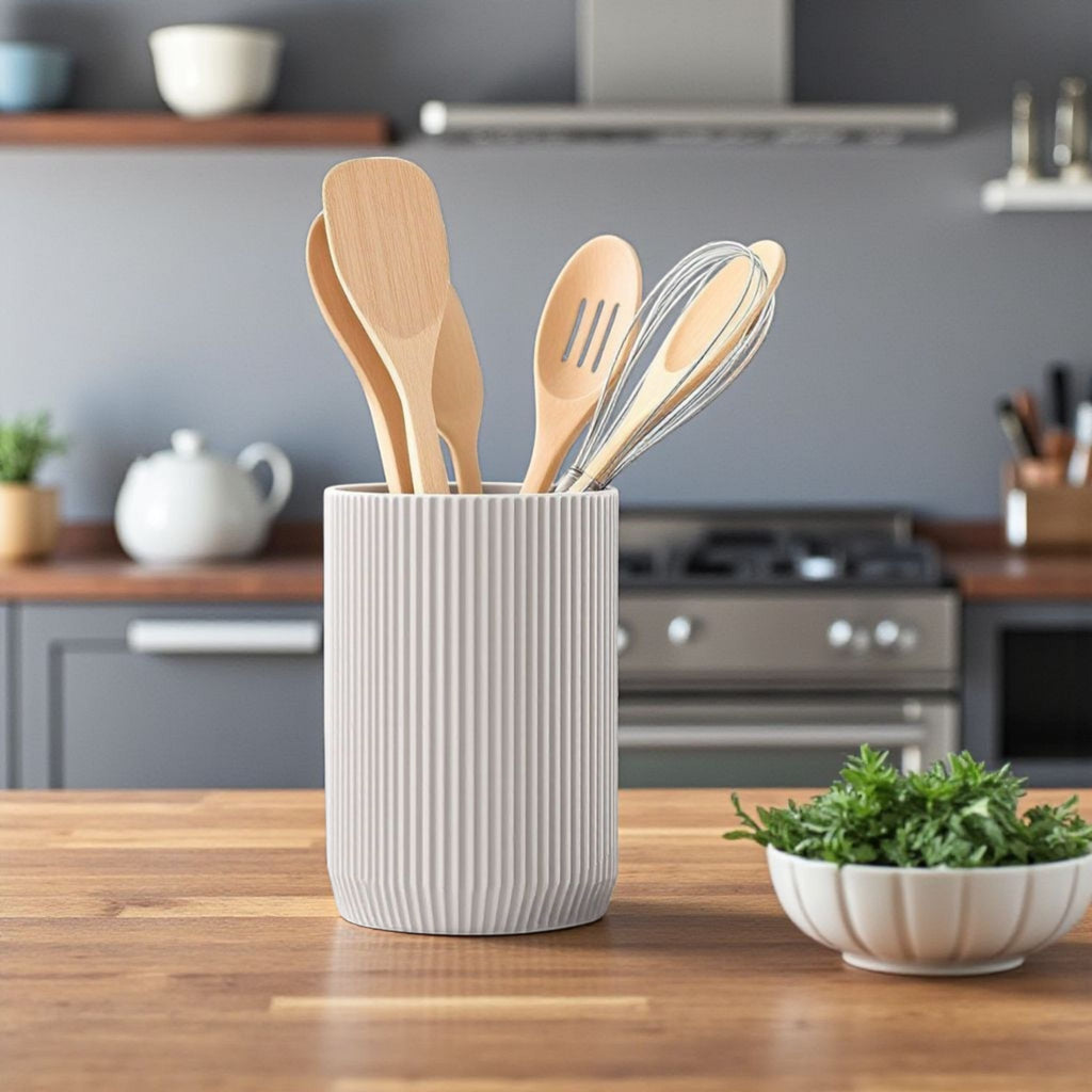 Kitchen utensils in a white container on a wooden countertop with a kitchen background.