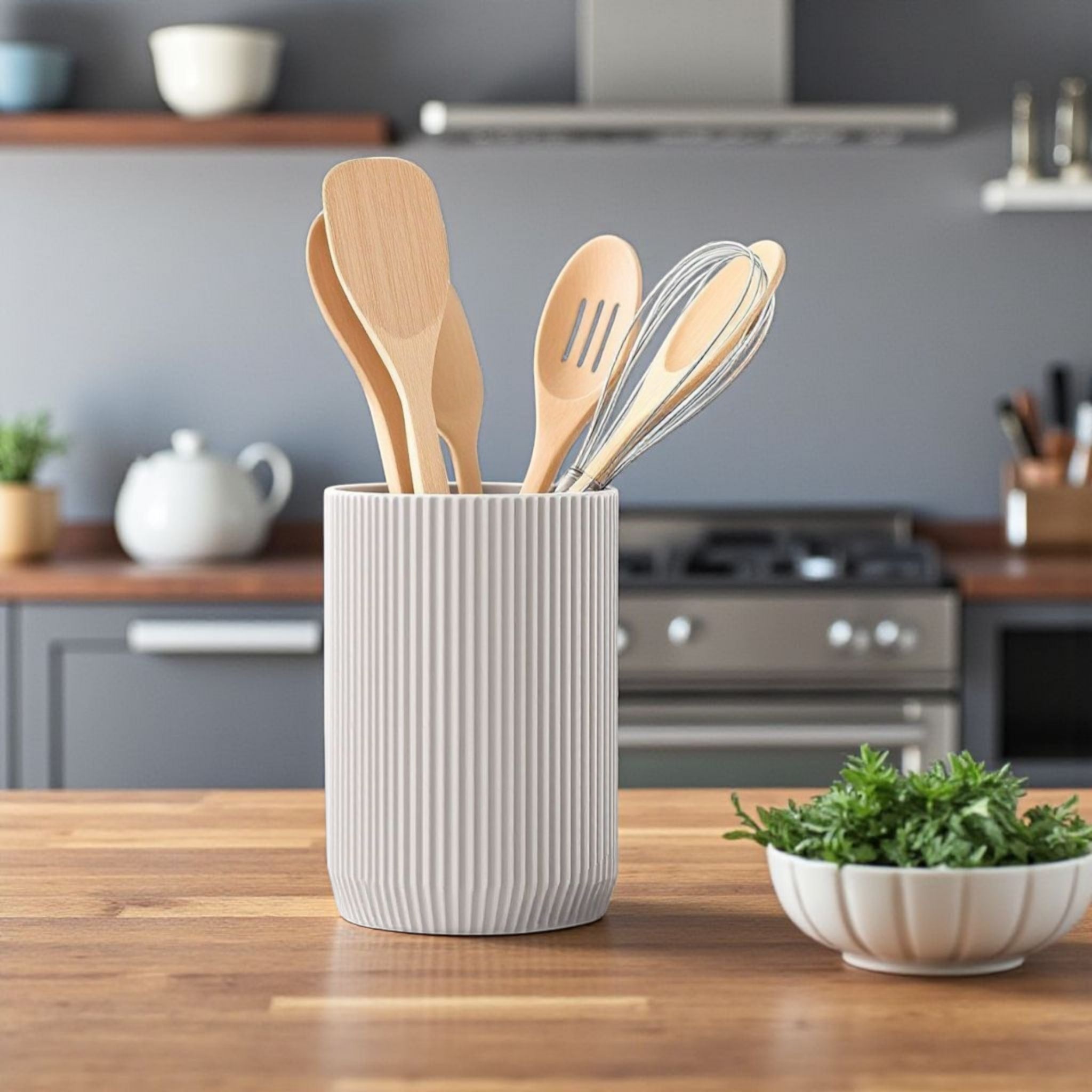 Kitchen utensils in a white container on a wooden countertop with a kitchen background.
