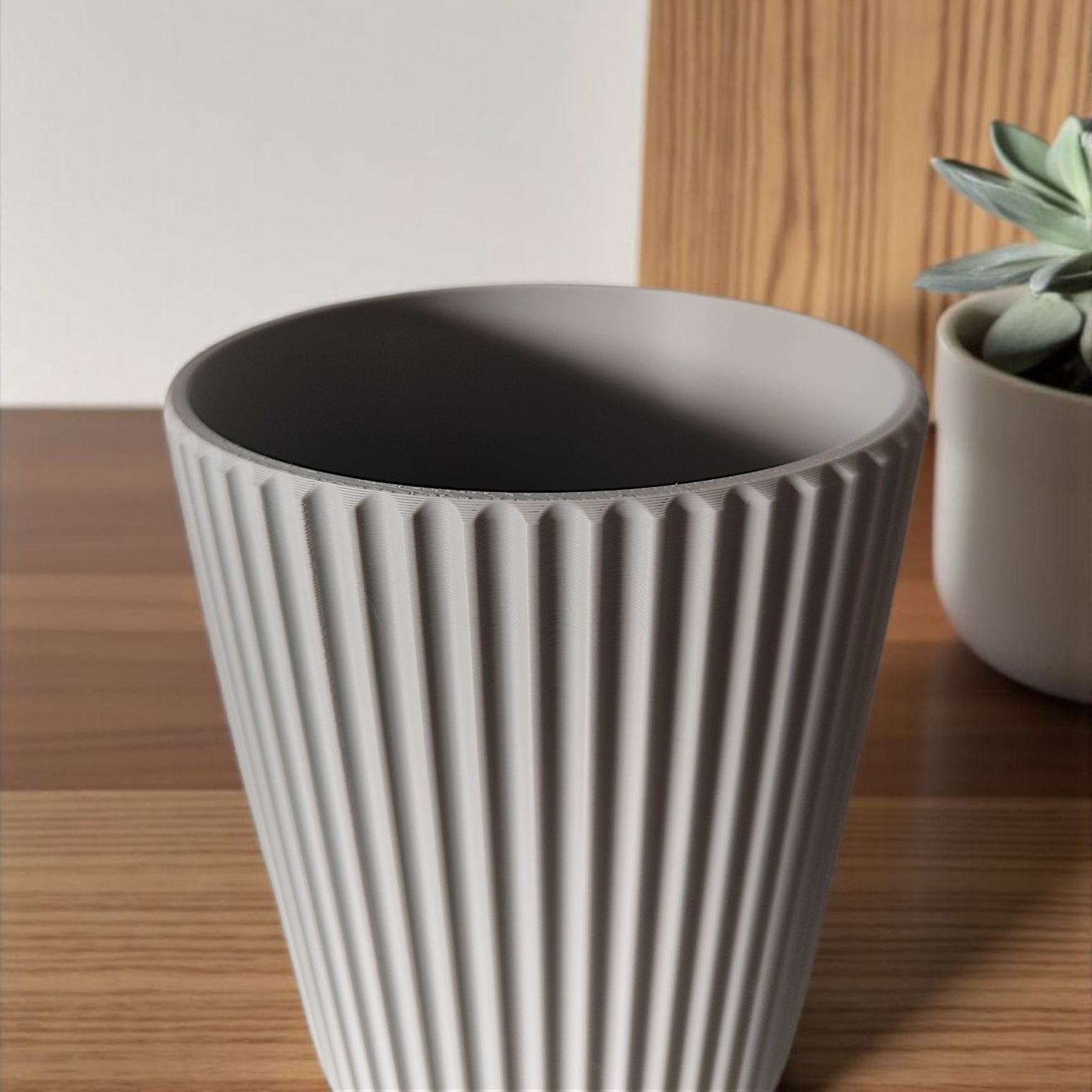 Gray ribbed planter on a wooden surface with a white wall background