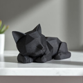 Black geometric cat sculpture on a white surface with a blurred background