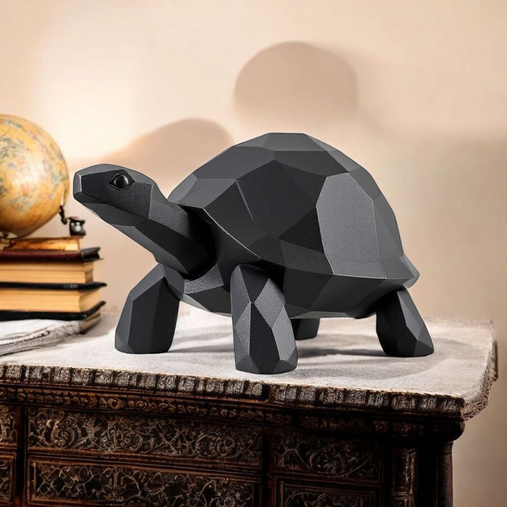 Geometric black turtle sculpture on a decorative table with books and a globe in the background.