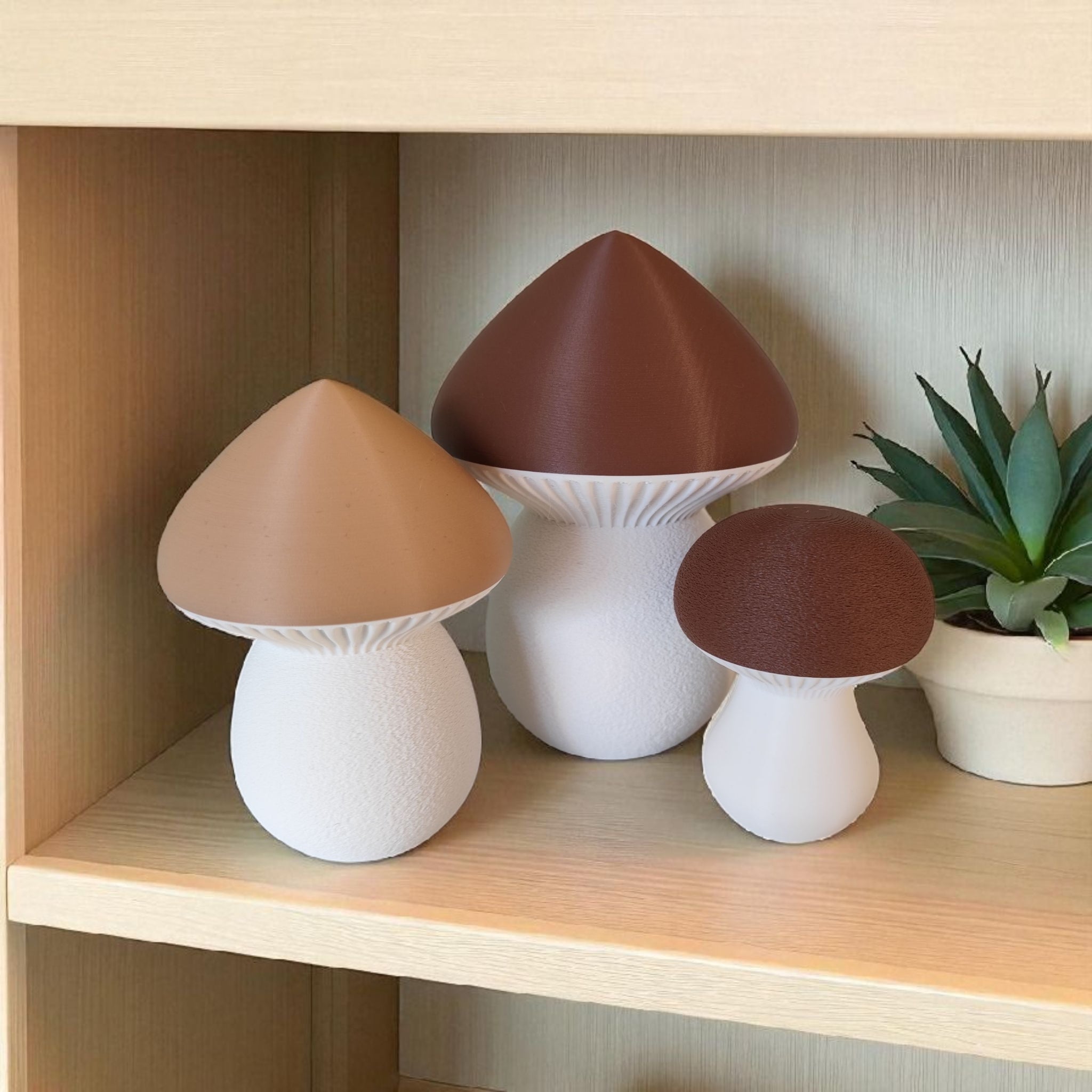 Three mushroom-shaped lamps on a wooden shelf with a plant in the background
