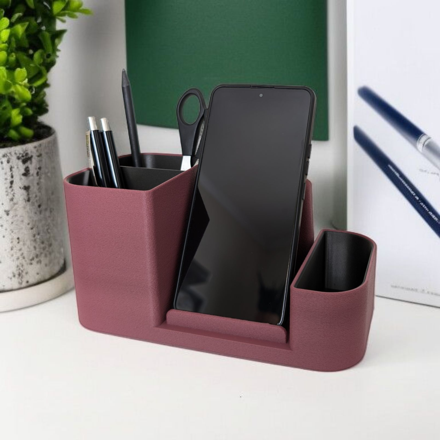 Purple desk organizer with phone stand, pen holder, and scissors on a white surface.