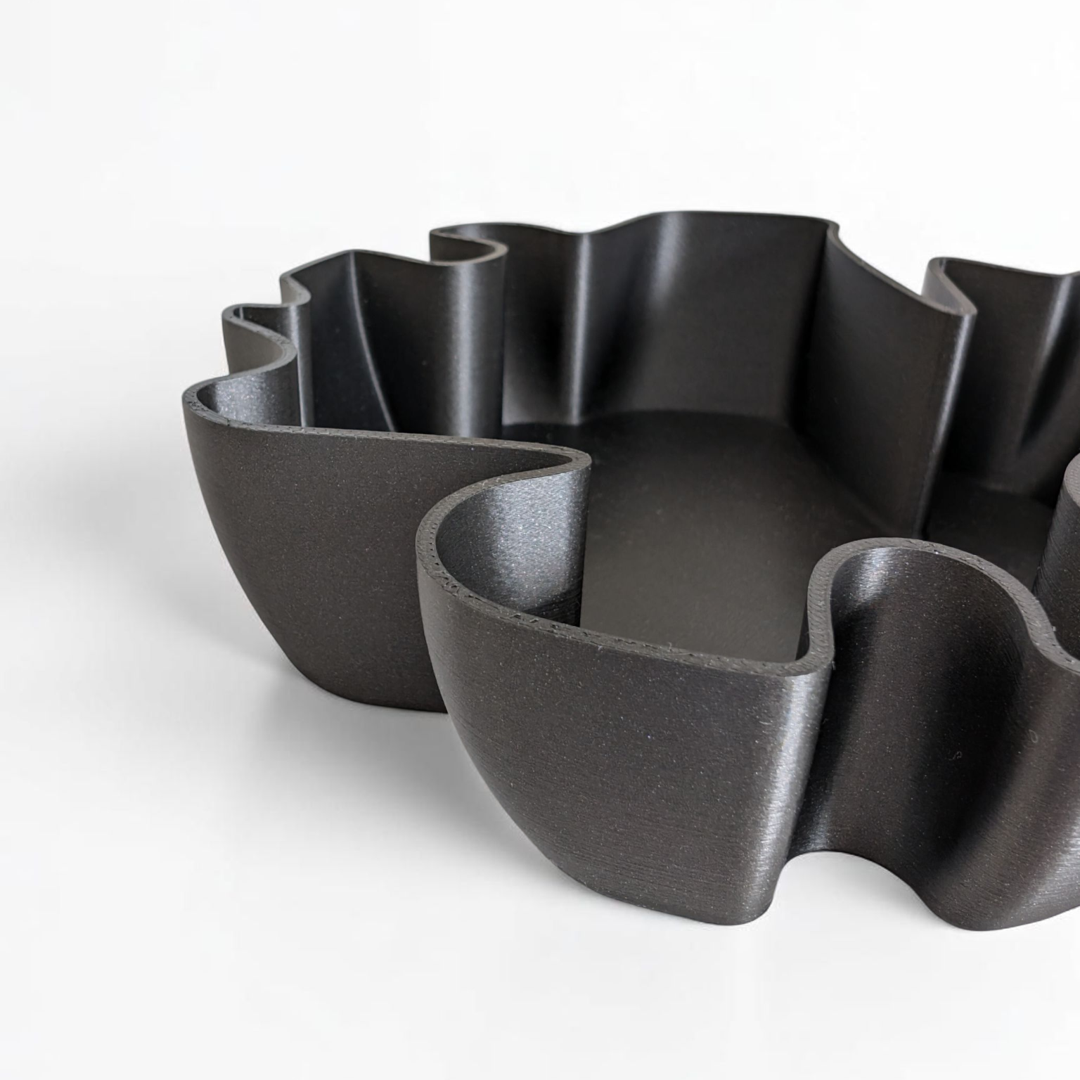 Set of black wavy ceramic bowls on a white background