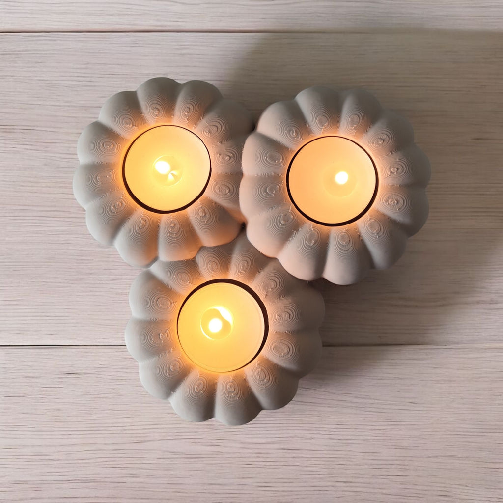 Three lit candles in decorative ceramic holders on a wooden surface