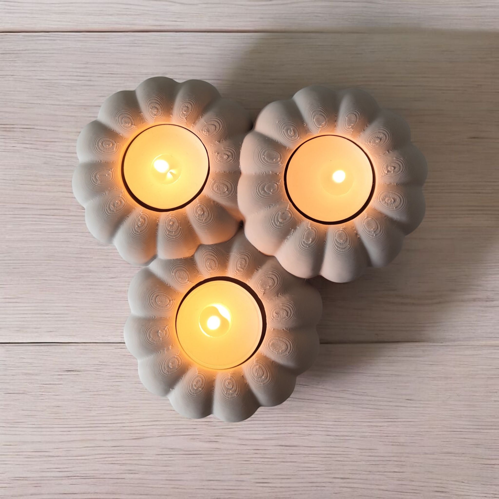 Three lit candles in decorative ceramic holders on a wooden surface