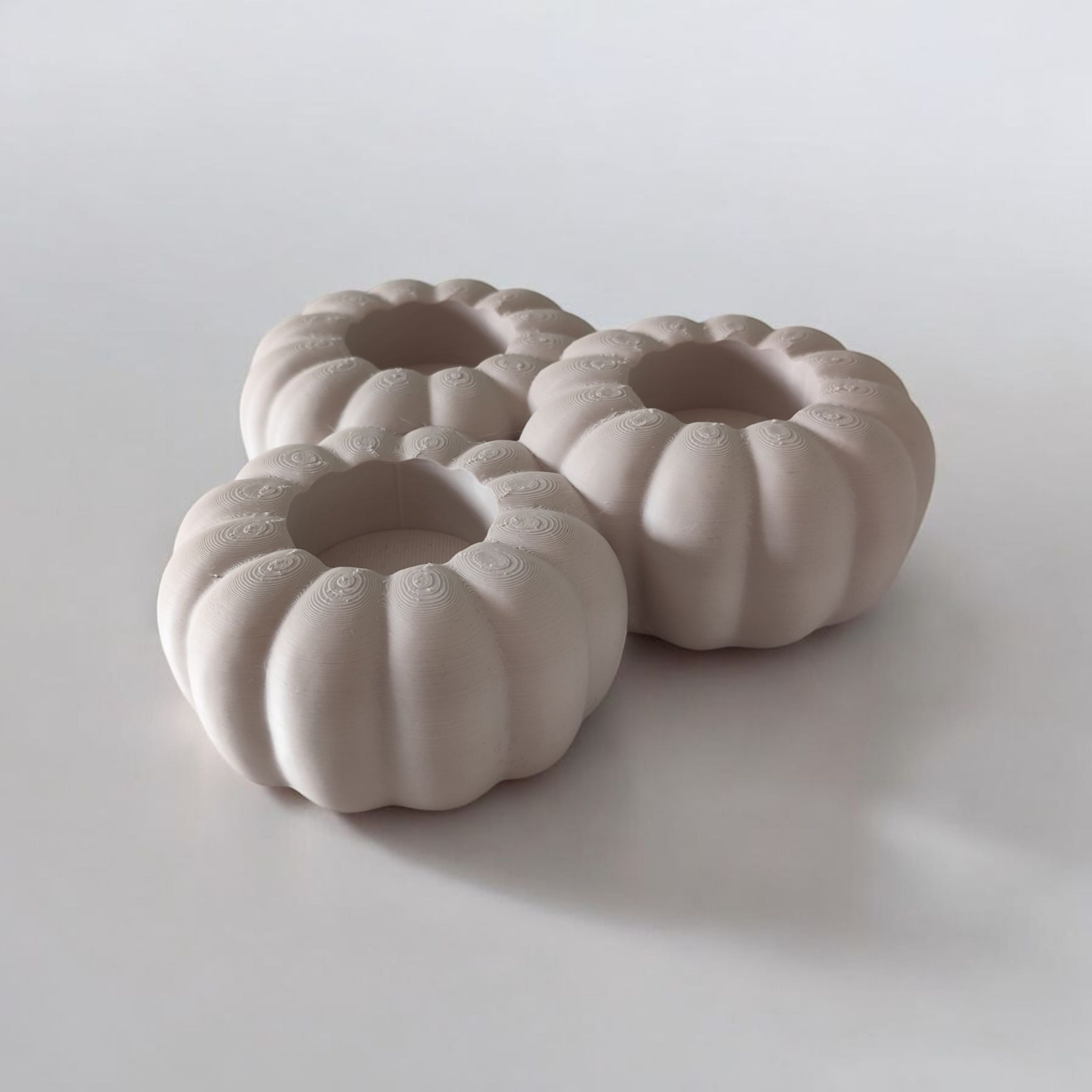 Three ceramic pumpkin-shaped candle holders on a white background