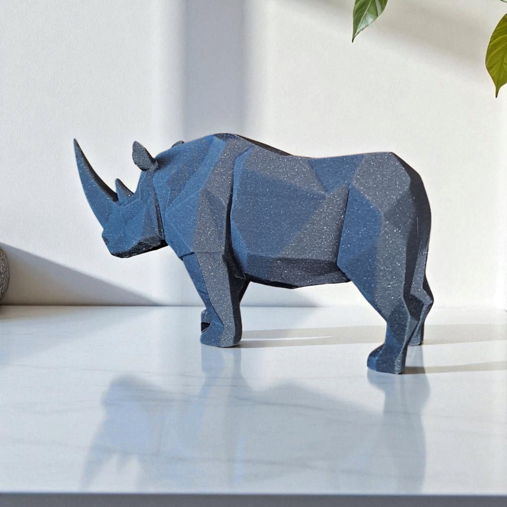 Blue geometric rhinoceros sculpture on a white surface with a light gray background