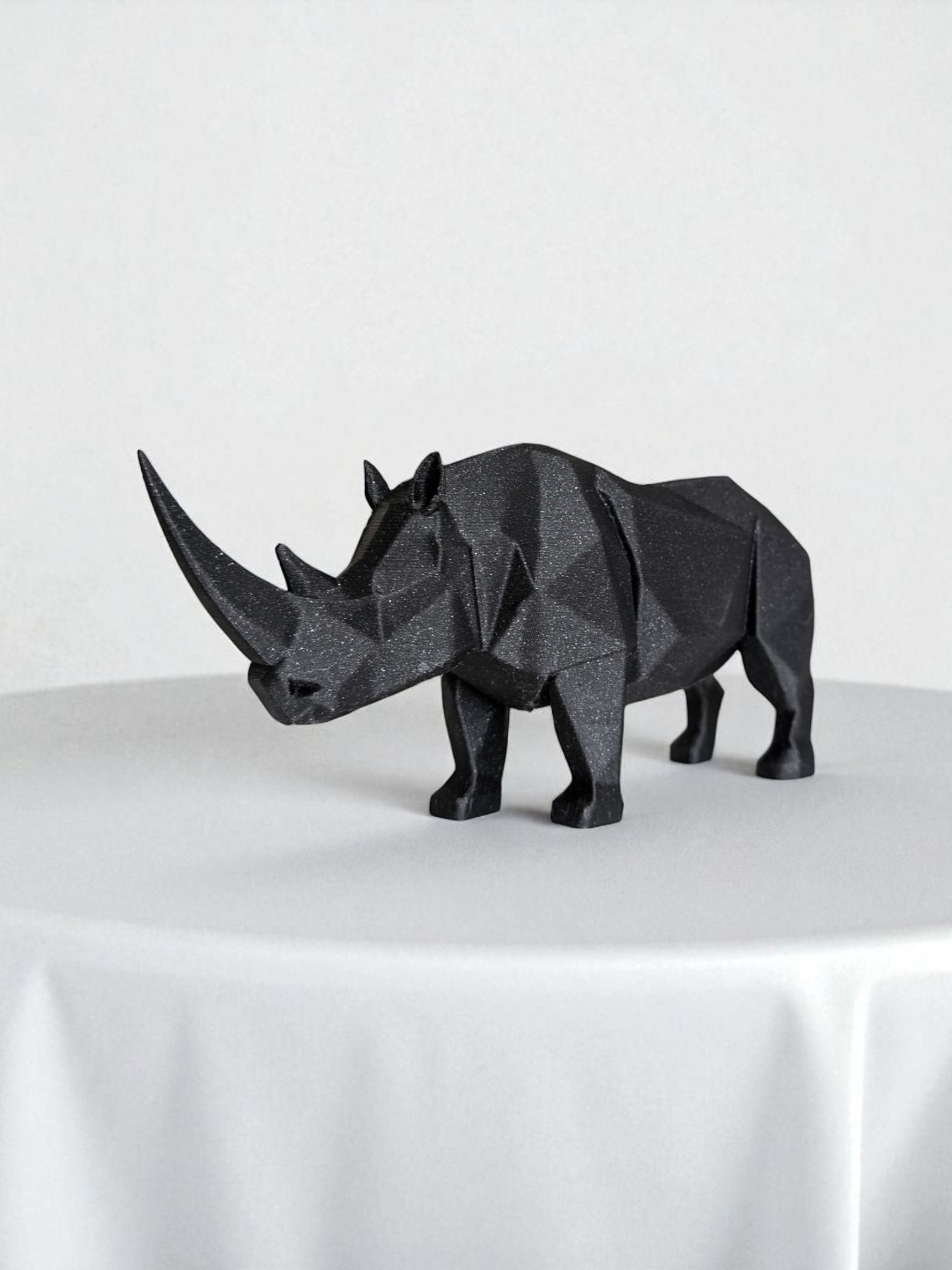Black geometric rhinoceros model on a white surface with a white background