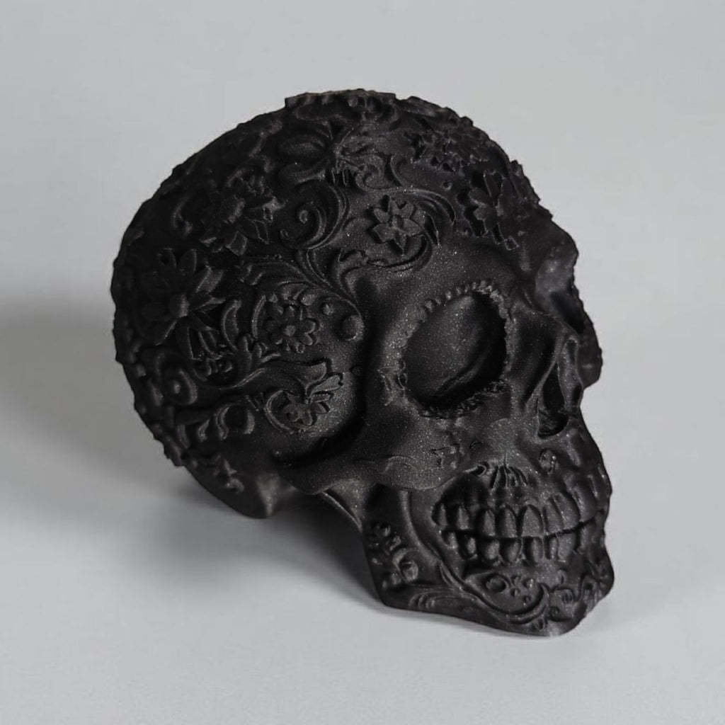 Decorative black skull with intricate designs on a gray background