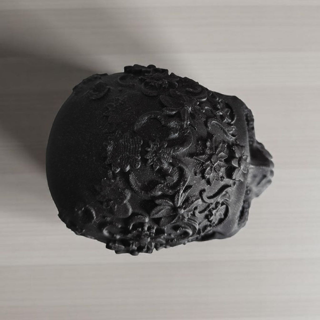 Black decorative object with floral patterns on a light gray background
