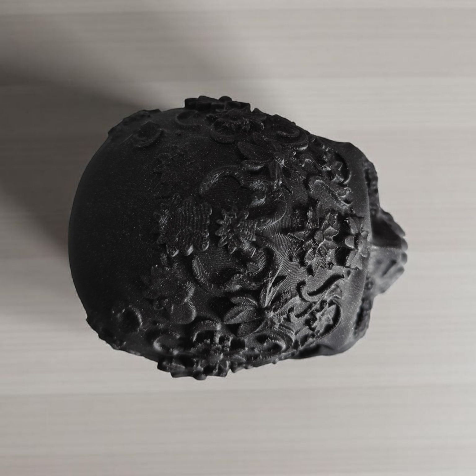 Black decorative object with floral patterns on a light gray background