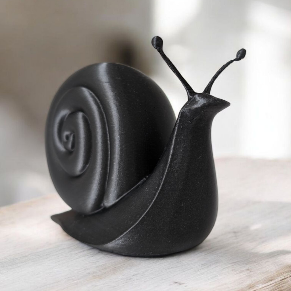 Black snail sculpture on a wooden surface with a blurred background