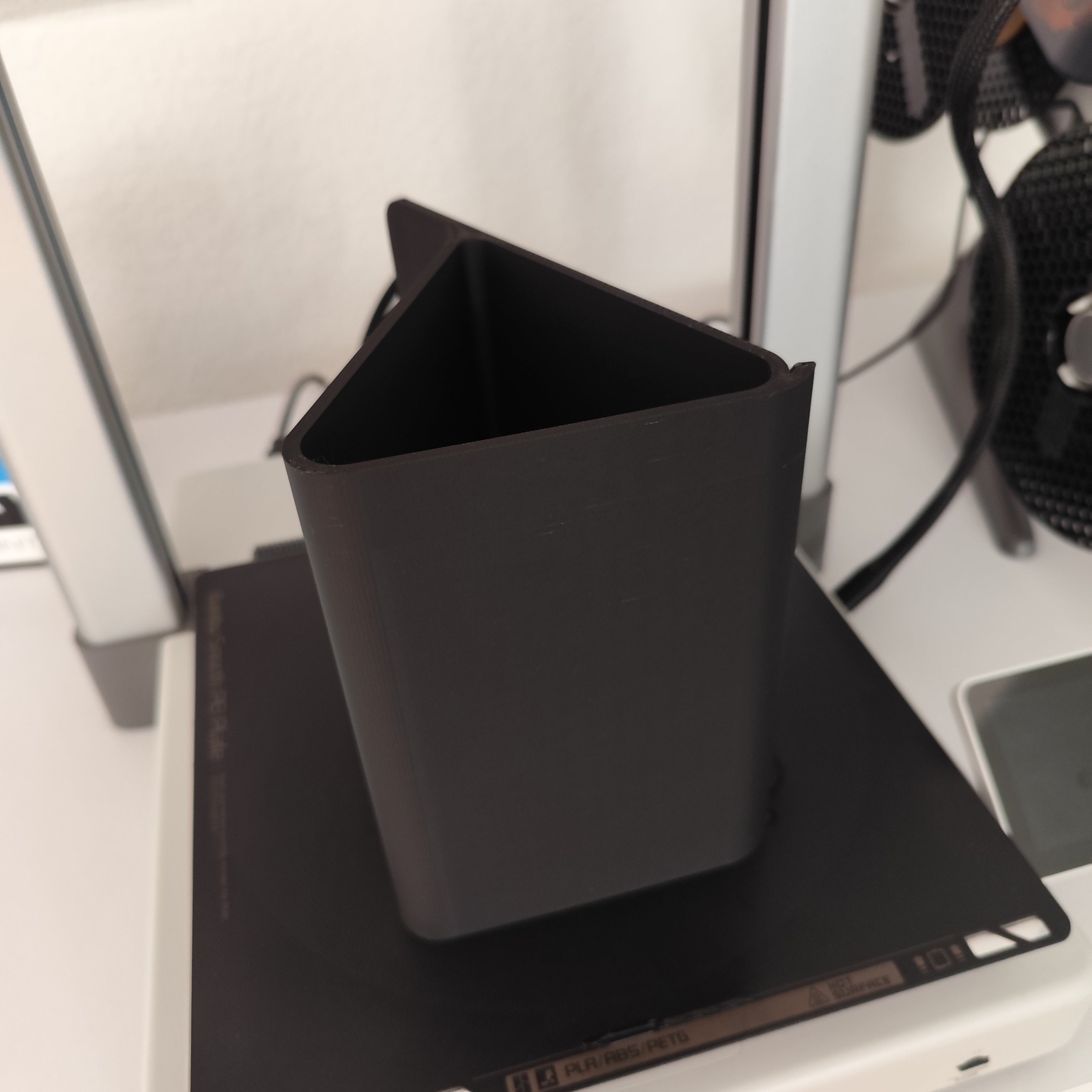Black office holder on a desk with computer equipment in the background