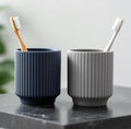 Set of two ribbed toothbrush cups on a marble countertop.