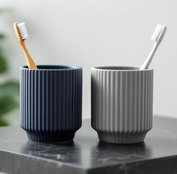 Set of two ribbed toothbrush cups on a marble countertop.