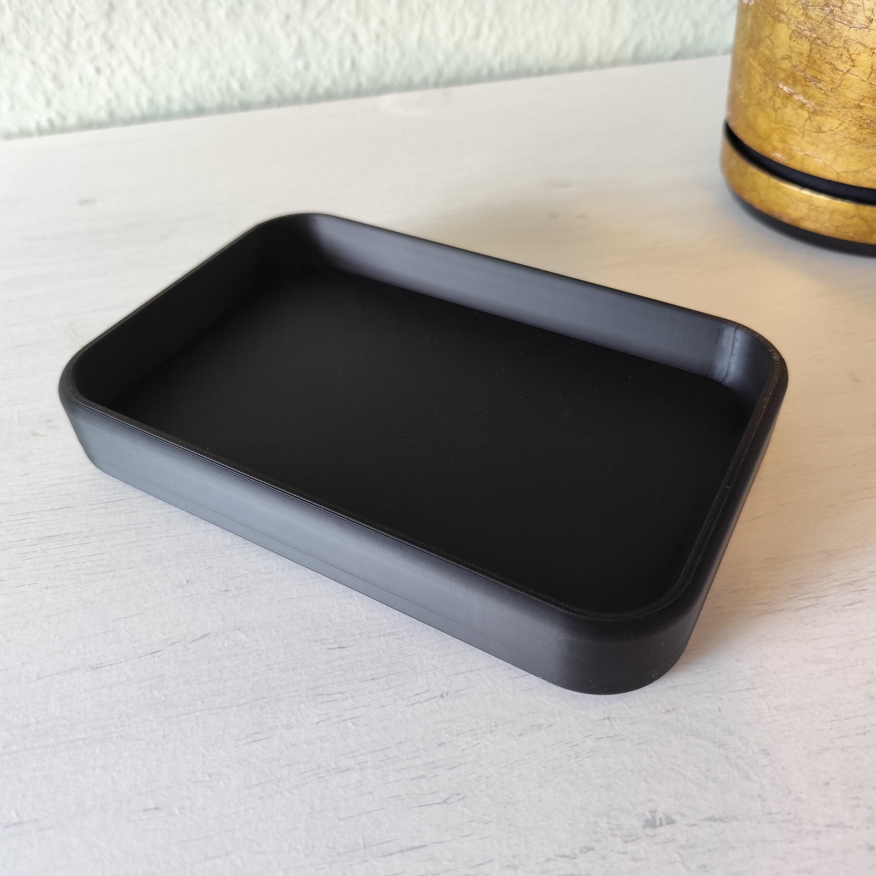 Black rectangular tray on a light wooden surface with a white textured background